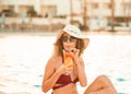 Pretty woman wearing a hat enjoying a cocktail in a pool