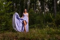 Pretty woman wearing a long purple dress and standing in the woods Royalty Free Stock Photo