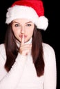 Pretty woman wearing santa hat saying shh