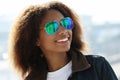 Pretty woman wearing sunglasses with perfect teeth and dark clean skin having rest outdoors Royalty Free Stock Photo