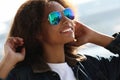 Pretty african woman wearing sunglasses with perfect teeth and dark clean skin having rest outdoors Royalty Free Stock Photo