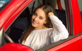 Pretty woman wearing a white blouse and posing for camera while her arm is over the window of her red car Royalty Free Stock Photo