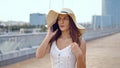 Pretty woman wearing white dress and pamela hat walking