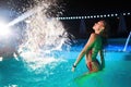 Pretty woman in wet bikini dancing and hanging out with friends at night pool party. People having fun splashing water Royalty Free Stock Photo