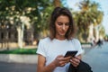 Pretty woman writes message on mobile smartphone while walking Park barcelona on a warm summer day, hipser girl listens to music Royalty Free Stock Photo