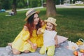 Pretty woman in yellow clothes play on green grass in park rest with little cute child baby girl hold soap bubble blower Royalty Free Stock Photo