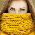 Pretty woman in a yellow knit scarf looking at the camera. Beaut