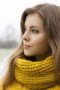 Pretty woman in a yellow knit scarf looks into the distance. Out