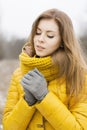 Pretty woman in a yellow knit scarf. Warm hands. Looking down.