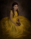 Pretty woman in the yellow long dress closeup with red rose in her hands. Beauty and the beast cosplay Royalty Free Stock Photo
