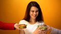 Pretty woman choosing salad instead of hamburger, healthcare vs junk food Royalty Free Stock Photo