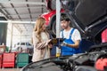 Pretty woman explain the problem of car to the professional vehicle maintenance man in uniform at garage. Car repair service