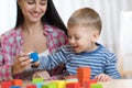 Pretty woman and her son child playing with building blocks