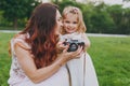 Pretty woman in light dress and little cute child baby girl take picture on retro vintage photo camera in park. Mother Royalty Free Stock Photo