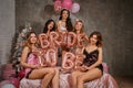 Ladies in sexy lingerie and bride in veil, enjoying a hen-party, sitting on bed, holding balloons, smiling. New year Royalty Free Stock Photo