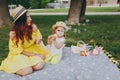 Pretty woman in yellow dress play on green grass in park, rest with little cute child baby girl hold soap bubble blower Royalty Free Stock Photo