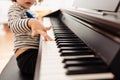 Pretty 3-year-old girl plays the keys of a piano and reads the sheet music with difficulty Royalty Free Stock Photo