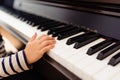 Pretty 3-year-old girl plays the keys of a piano and reads the sheet music with difficulty Royalty Free Stock Photo