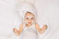 Pretty 2 years old girl child relaxing in the bedroom after shower, lying on the bed, wearing white towel on head and Royalty Free Stock Photo