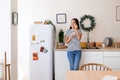 Pretty young woman eating natural yogurt while standing in the kitchen at home Royalty Free Stock Photo