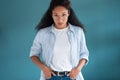 Pretty young african american woman looking at camera with serious expression while posing over blue background Royalty Free Stock Photo