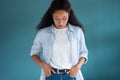 Pretty young african american woman looking down with serious expression while posing over blue background Royalty Free Stock Photo