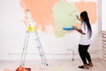 Pretty young african american woman with painting roller indoors. Redecoration, renovation, apartment repair and Royalty Free Stock Photo