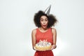 Pretty young afro american woman in silver party hat is celebrating her birthday and blowing out the candles on Royalty Free Stock Photo