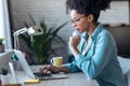 Pretty young afro woman shopping online with credit card with laptop while working on office at home Royalty Free Stock Photo