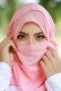 Pretty young asian Arabian woman wearing pink hijab confident in green nature outdoor. Portrait with beautiful muslim eyes girl.