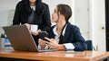 A pretty young Asian businesswoman talking with her female boss while working at her desk Royalty Free Stock Photo