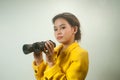 Pretty young Asian businesswoman in yellow suit holding a binoculars. Royalty Free Stock Photo