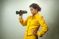 Pretty young Asian businesswoman in yellow suit holding a binoculars. Royalty Free Stock Photo