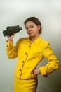 Pretty young Asian businesswoman in yellow suit holding a binoculars. Royalty Free Stock Photo