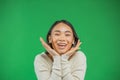Pretty young asian delighted woman holding her face in hands isolated on green background Royalty Free Stock Photo