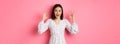 Pretty young asian woman in dress showing okay sign, praising and showing approval, looking satisfied, standing against Royalty Free Stock Photo