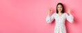 Pretty young asian woman in dress showing okay sign, praising and showing approval, looking satisfied, standing against Royalty Free Stock Photo