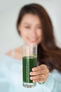 Pretty young asian woman drinking green fresh vegetable juice or Royalty Free Stock Photo