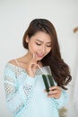 Pretty young asian woman drinking green fresh vegetable juice or Royalty Free Stock Photo