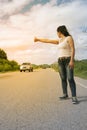 Pretty young Asian woman with hand up calling passing car. Royalty Free Stock Photo