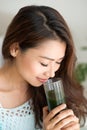 Pretty young asian woman holding green fresh vegetable juice or Royalty Free Stock Photo