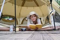 Pretty young asian woman resting, reading a book in camping tent. Travel, camping and vacation concept Royalty Free Stock Photo