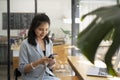 Pretty asian woman sitting in modern coffee shop and using smart phone. Royalty Free Stock Photo