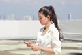 Pretty young Asian woman using mobile smart phone with modern skyscraper on background. Social network concept Royalty Free Stock Photo