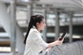 Pretty young Asian woman using mobile smart phone on street of city background. Social network concept Royalty Free Stock Photo