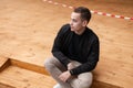 Pretty young attractive fashionable man in a spring stylish black jacket in beige trousers in sneakers posing sitting Royalty Free Stock Photo