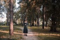Pretty young beautiful woman in dark dress and witch hat standing in middle of autumn woods or park. Halloween party Royalty Free Stock Photo
