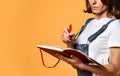 Pretty young beautiful woman standing, writing, take notes, holding textbook notebook organizer in hand and pen Royalty Free Stock Photo