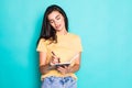 Pretty young beautiful woman standing, writing, take notes, holding textbook notebook organizer in hand and pen on turquoise Royalty Free Stock Photo