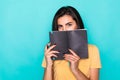 Pretty young beautiful woman standing, writing, take notes, holding textbook notebook organizer in hand and pen on turquoise Royalty Free Stock Photo